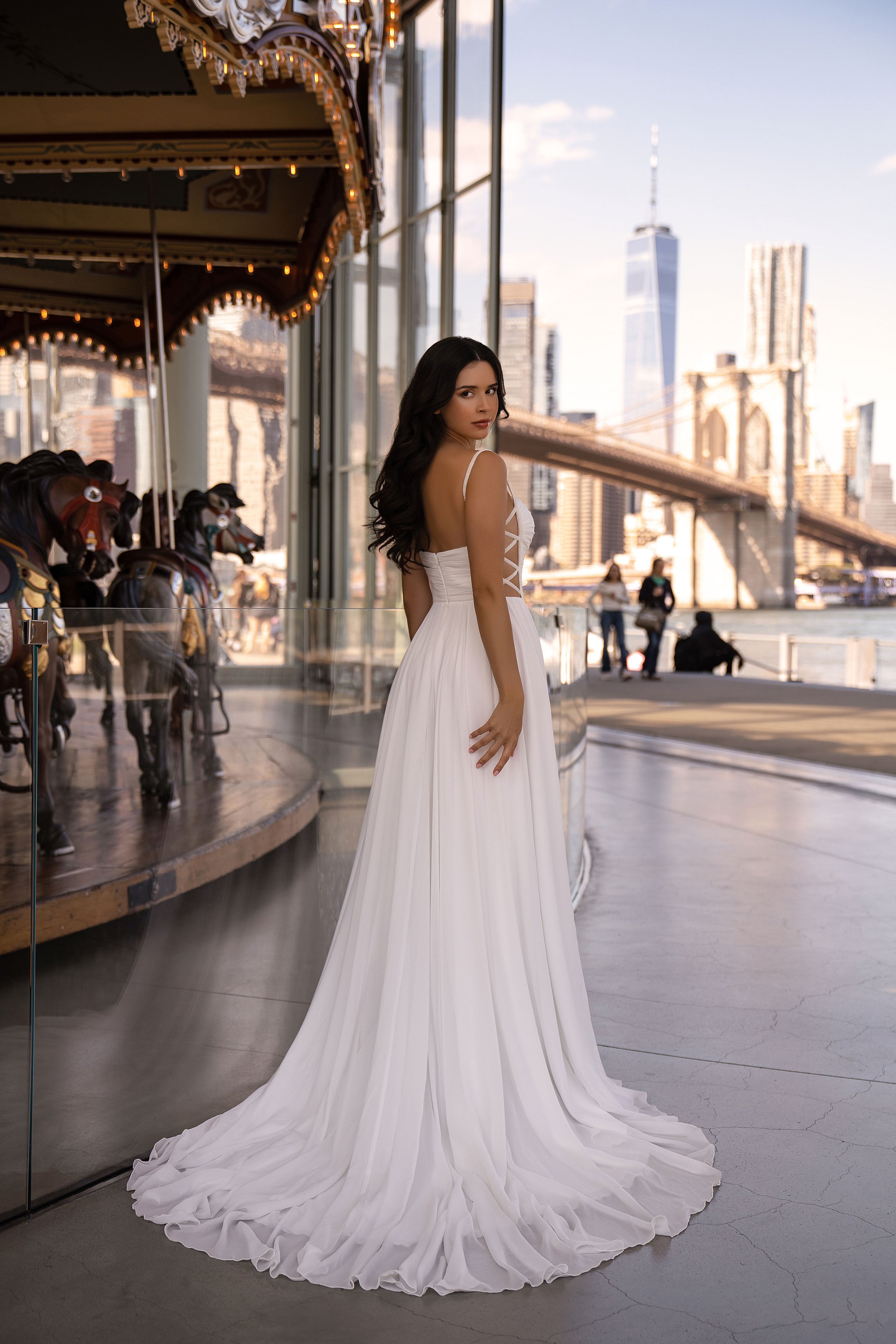 Ivory A-line wedding dress with thin shoulder straps, an open back, and a long flowing train