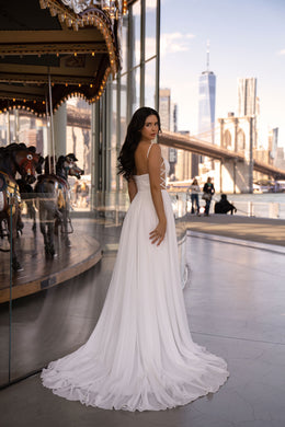 Ivory A-line wedding dress with thin shoulder straps, an open back, and a long flowing train