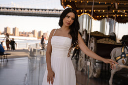 Ivory wedding dress with a straight ruched neckline, lace-up side cutouts, and flowing A-line skirt