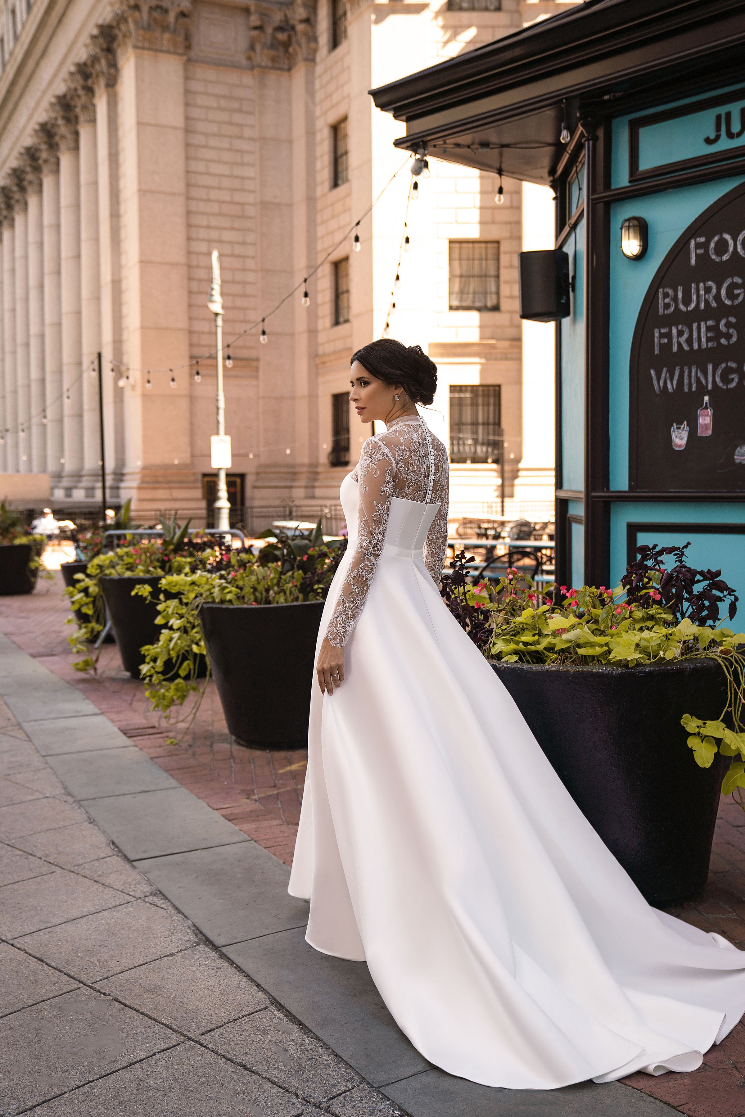 Side profile of a white A-line wedding dress with long lace sleeves and a sweeping floor-length train