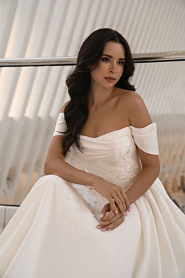 Ivory wedding dress with an off-the-shoulder draped neckline, short sleeves, and a sparkling embellished bodice