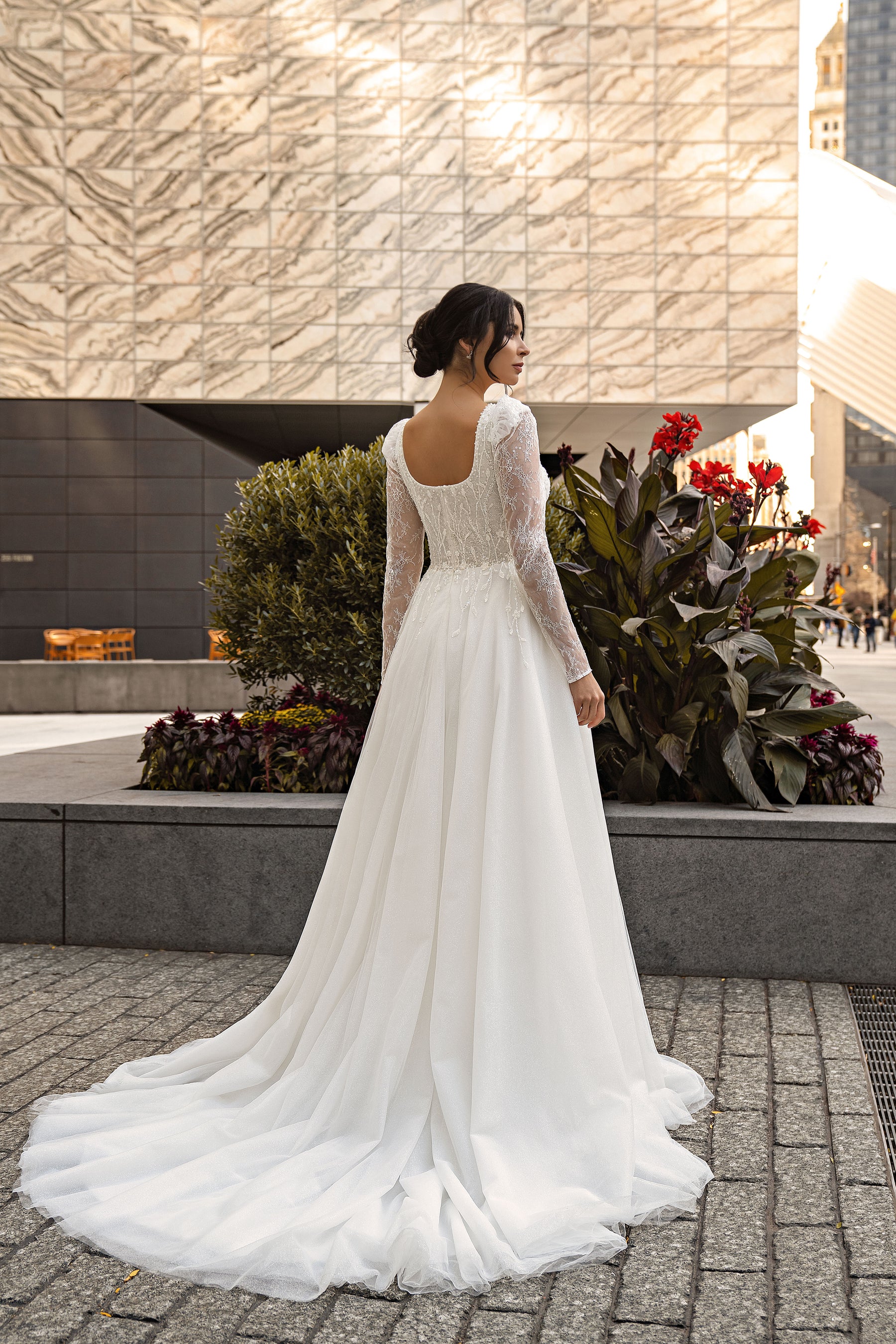 Open low back and long lace sleeves on an ivory A-line wedding dress with a flowing train