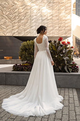 Open low back and long lace sleeves on an ivory A-line wedding dress with a flowing train