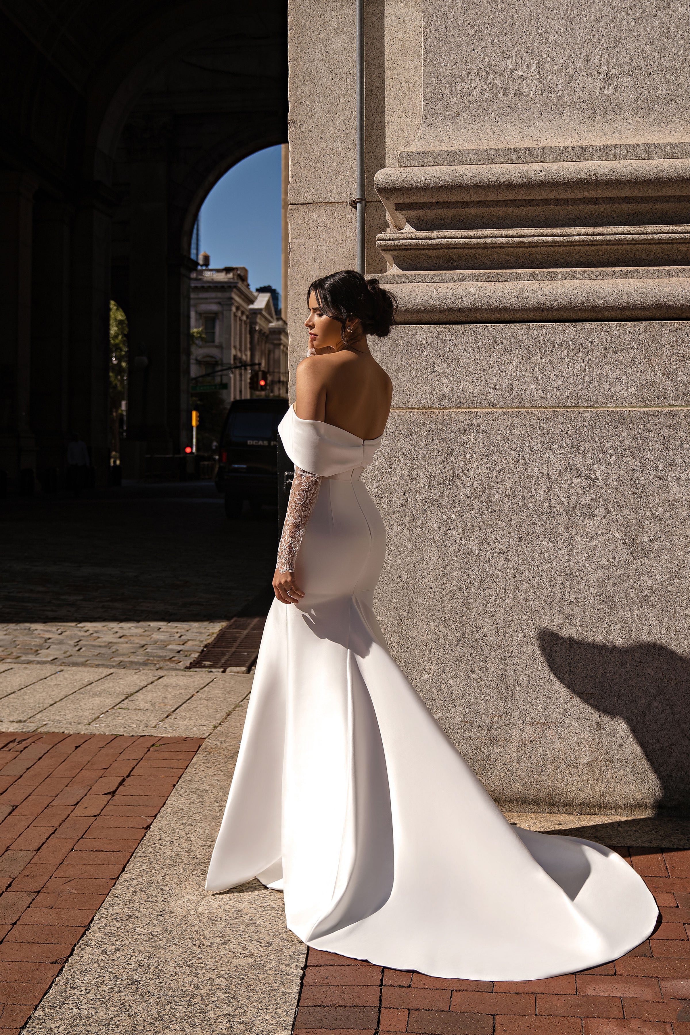 Bare-back ivory mermaid wedding dress with off-the-shoulder lace sleeves and a long flowing train