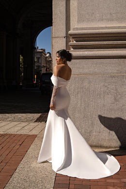 Bare-back ivory mermaid wedding dress with off-the-shoulder lace sleeves and a long flowing train