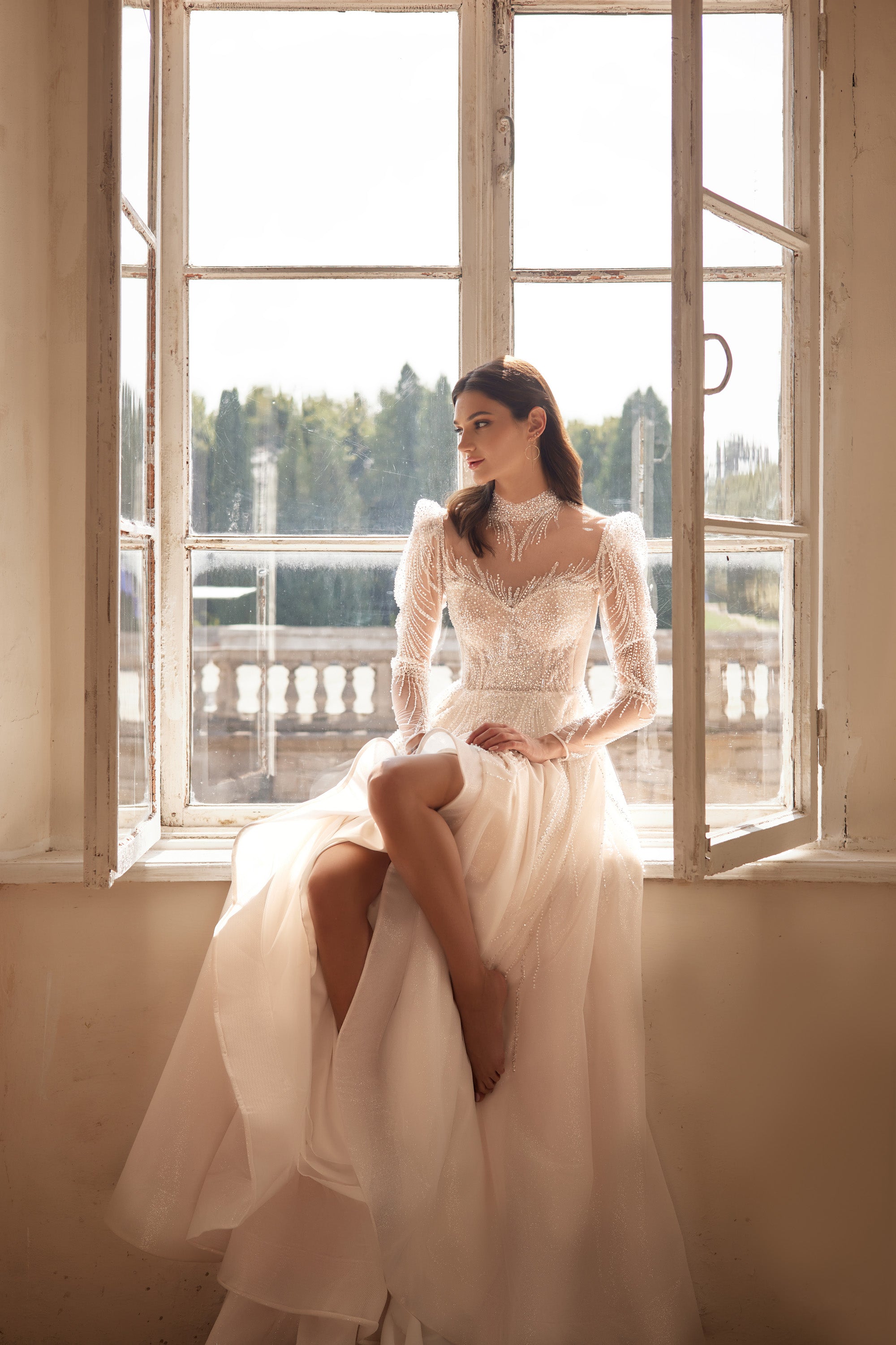 Ivory wedding dress with a beaded illusion neckline, long sheer sleeves, and a flowing full skirt