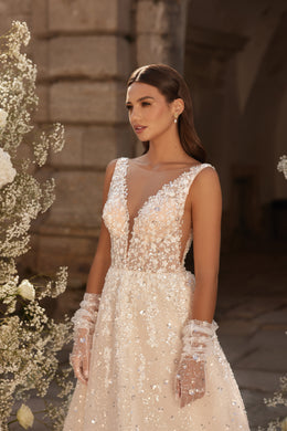 Ivory A-line wedding dress with a sheer V-neck, sleeveless bodice, floral beadwork, and detachable cuffs