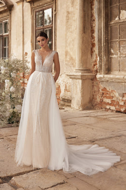 Beaded V-neck wedding dress with a sheer overskirt, fitted sheath skirt, and sweeping train