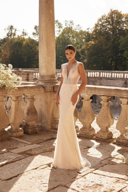 Ivory sheath wedding dress with a beaded V-neckline, sleeveless bodice, and fitted silhouette