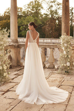 Ivory wedding dress with a beaded sheer V-back and flowing overskirt forming a long train