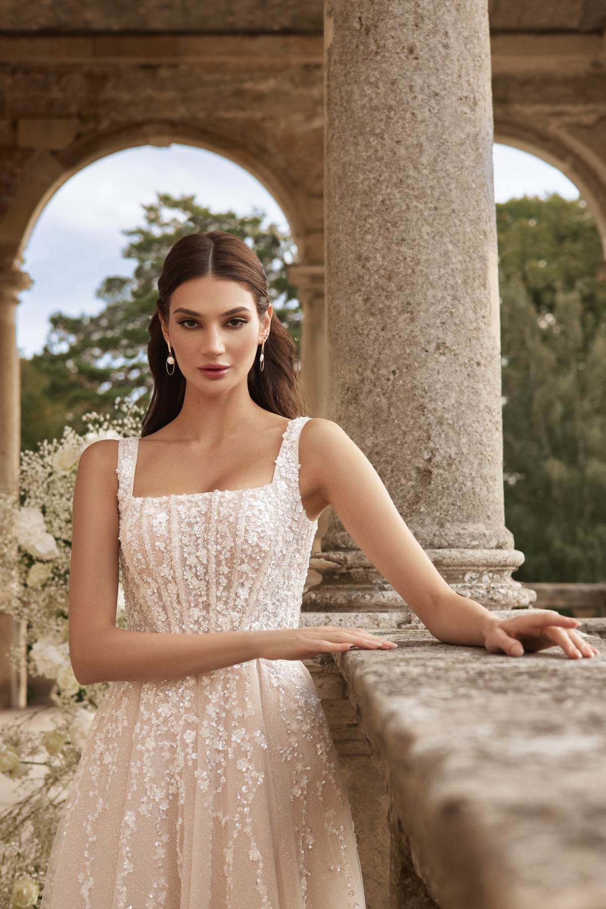 Square-neck ivory wedding dress with wide straps and shimmering floral embellishments on the bodice