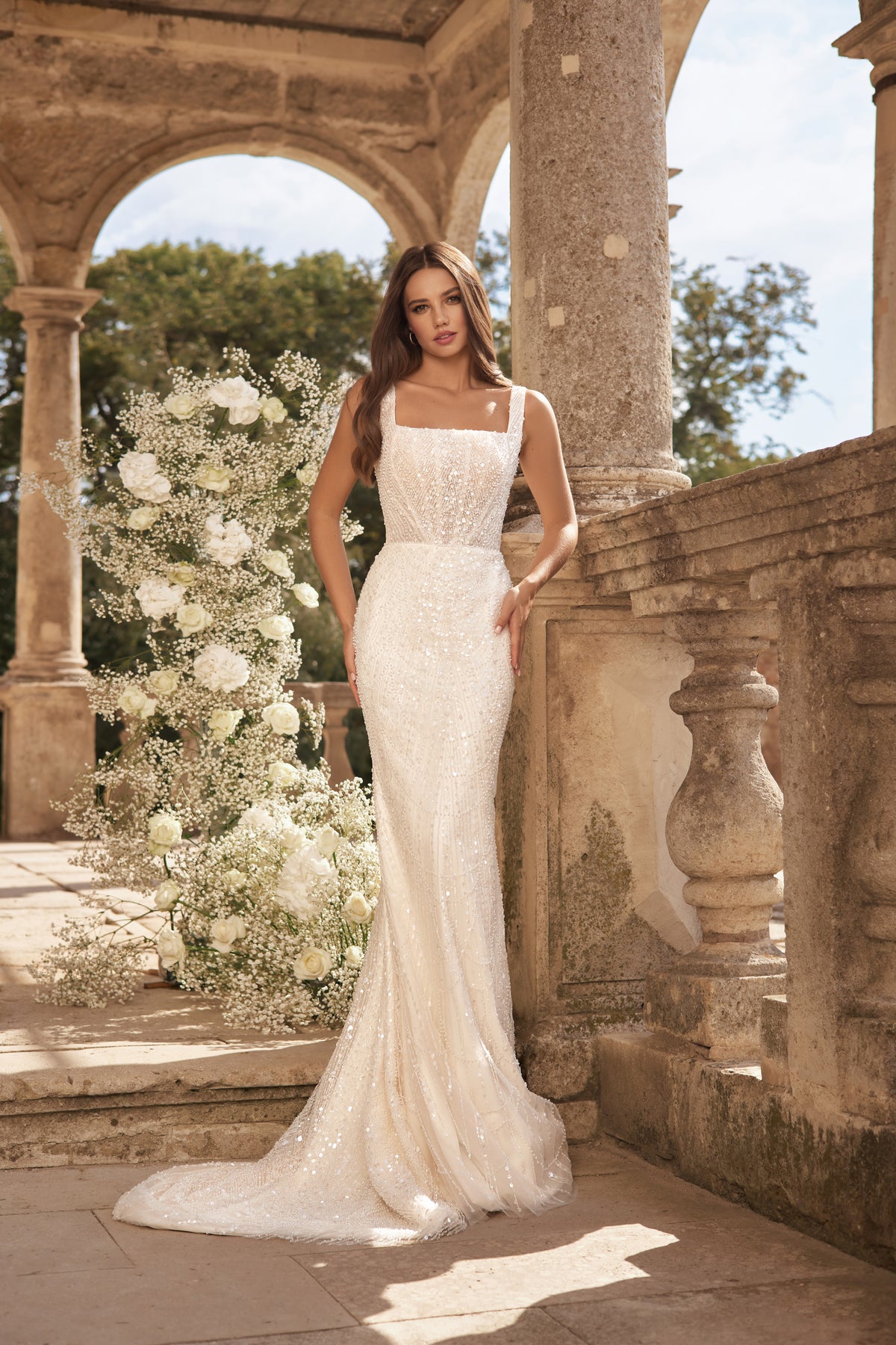 Ivory sheath wedding dress with a square neckline, slim straps, sparkling beadwork, and a sweeping train