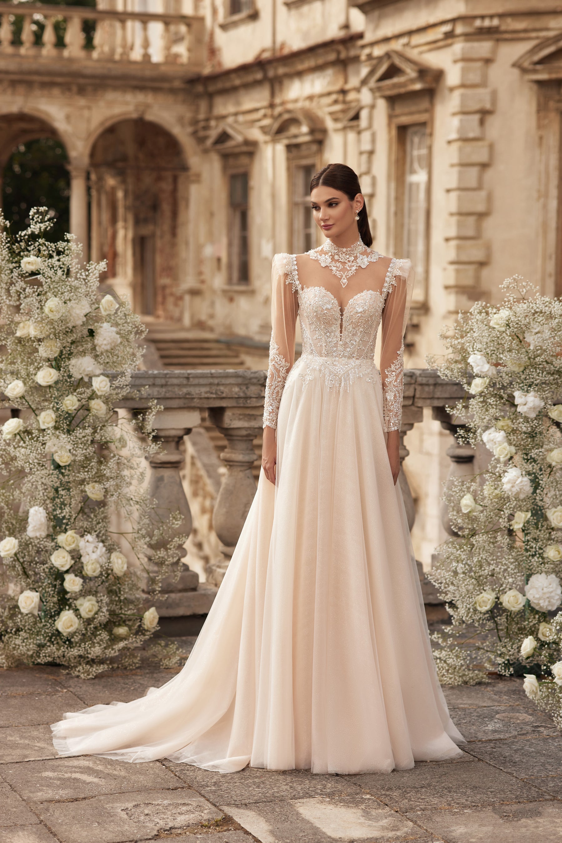 Ivory A-line wedding dress with a beaded bodice, sheer lace sleeves, V-neckline, and sweeping train