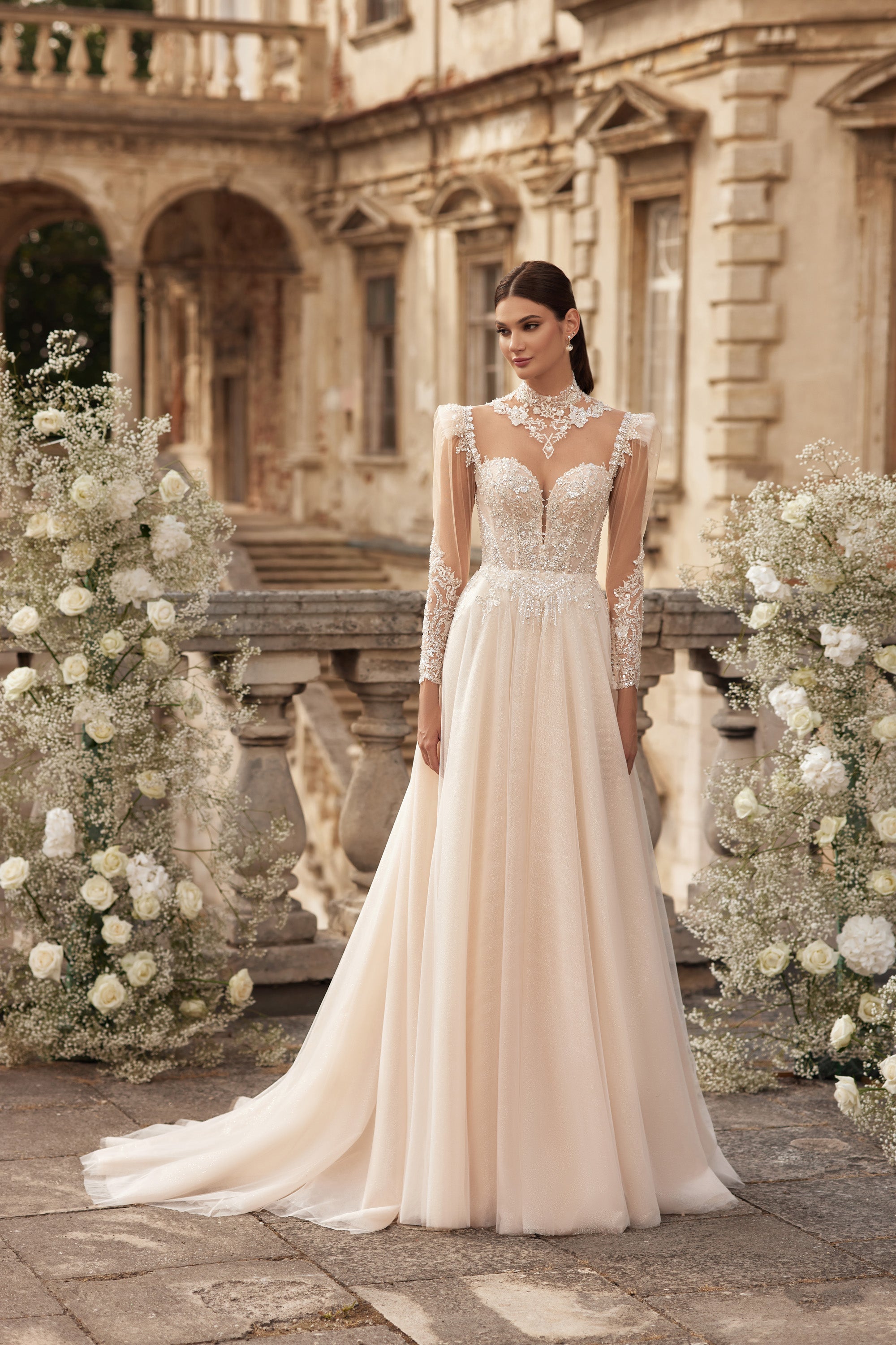 Ivory A-line wedding dress with a beaded bodice, sheer lace sleeves, V-neckline, and sweeping train