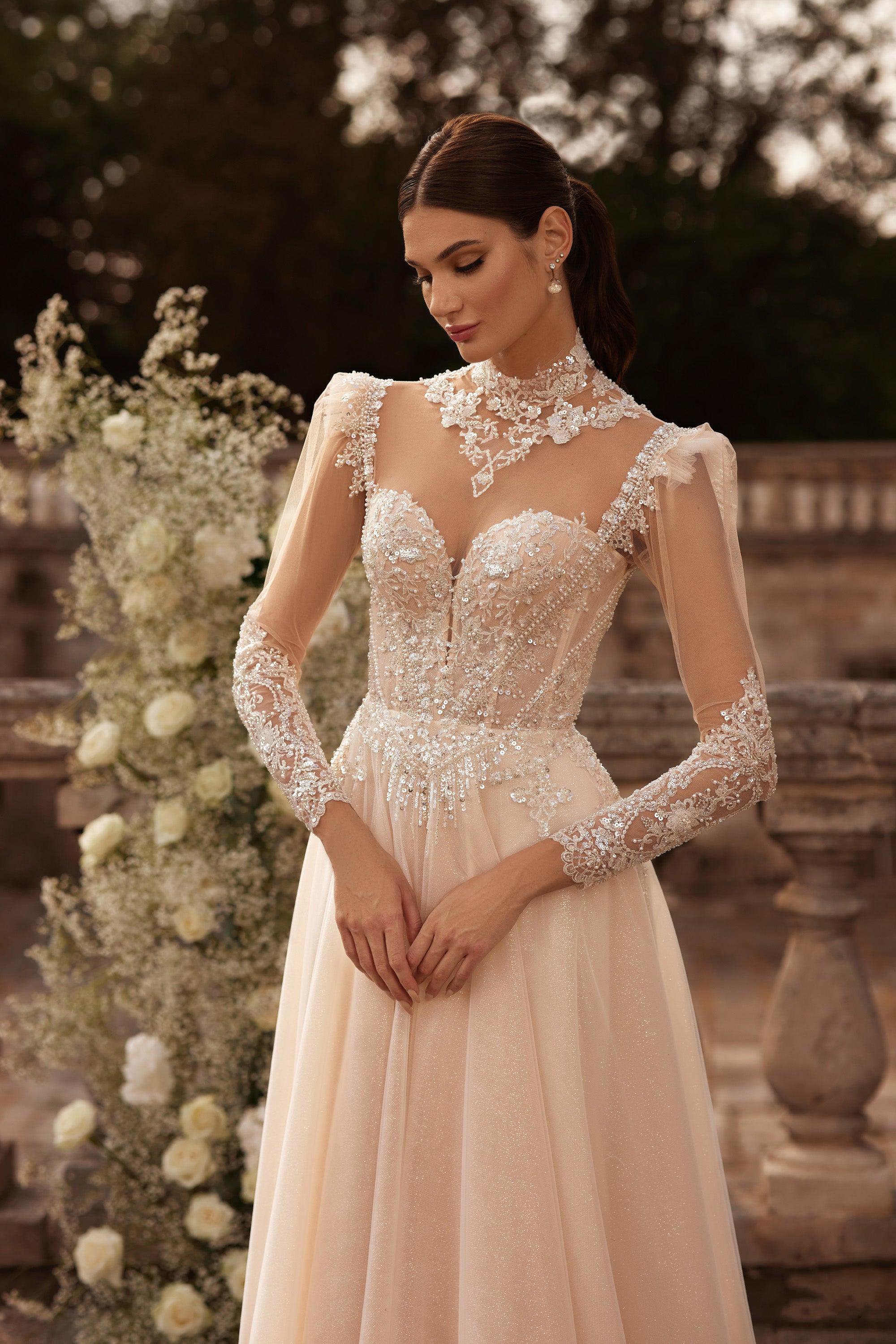 Beaded ivory wedding dress with a sheer illusion neckline, long lace sleeves, and A-line skirt