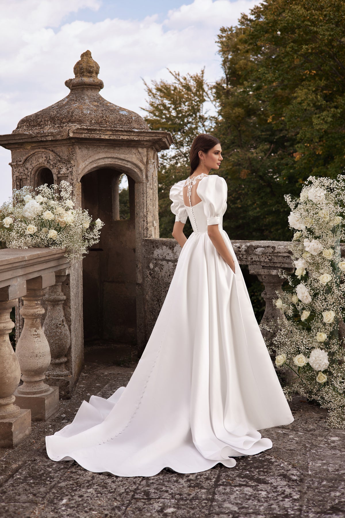 Ivory wedding dress with puff sleeves, an open back, and a long flowing train