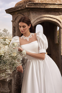 Close-up of an ivory wedding dress with puff sleeves, a square neckline, and floral lace trim
