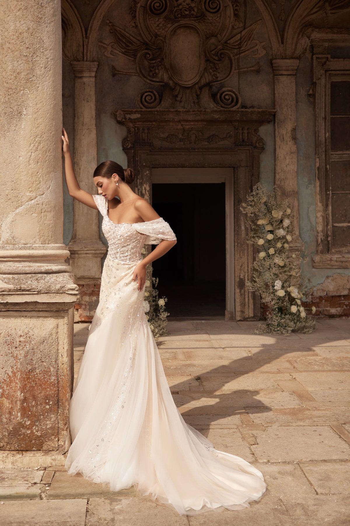 Ivory mermaid wedding dress with an off-the-shoulder neckline, embellished bodice, and sweeping train