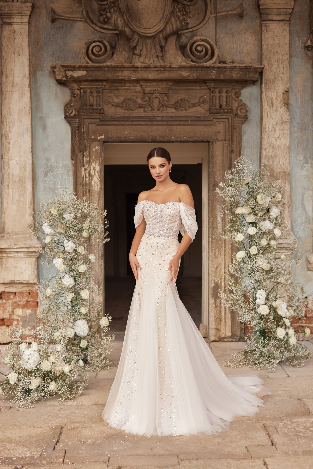 Beaded ivory wedding dress with draped off-the-shoulder sleeves, fitted mermaid skirt, and long train