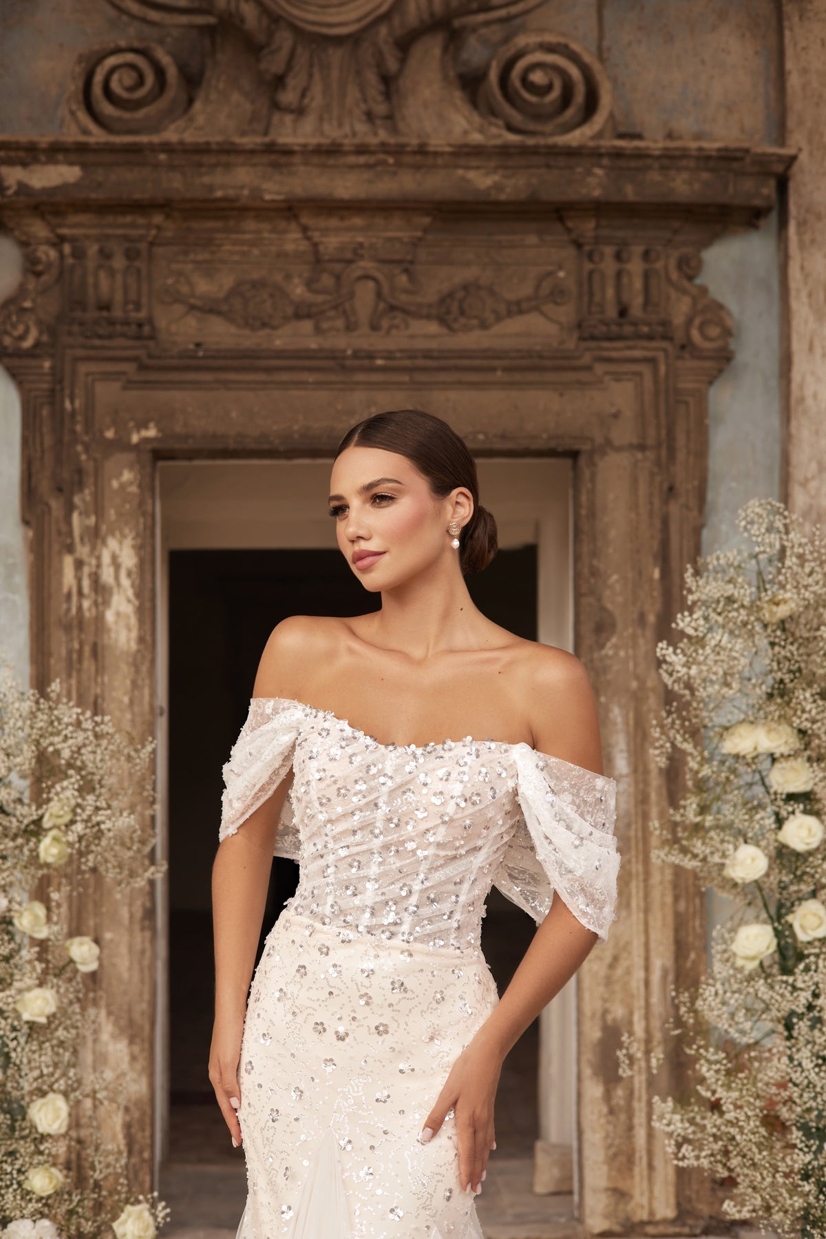 Close-up of sparkling beadwork and an off-the-shoulder neckline on an ivory wedding dress