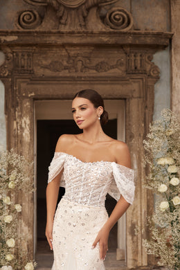 Close-up of sparkling beadwork and an off-the-shoulder neckline on an ivory wedding dress