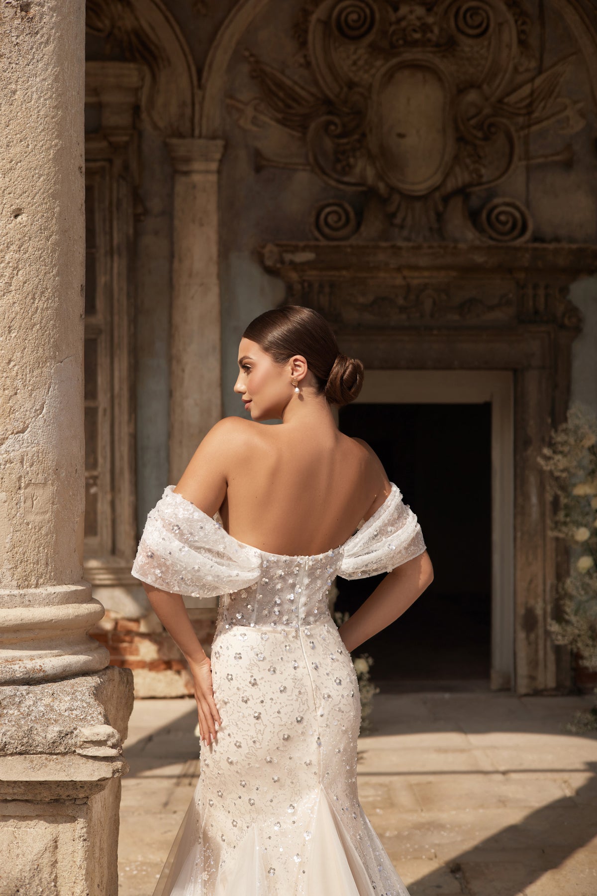 Back of an ivory mermaid wedding dress showing the exposed upper back, draped sleeves, and beaded bodice