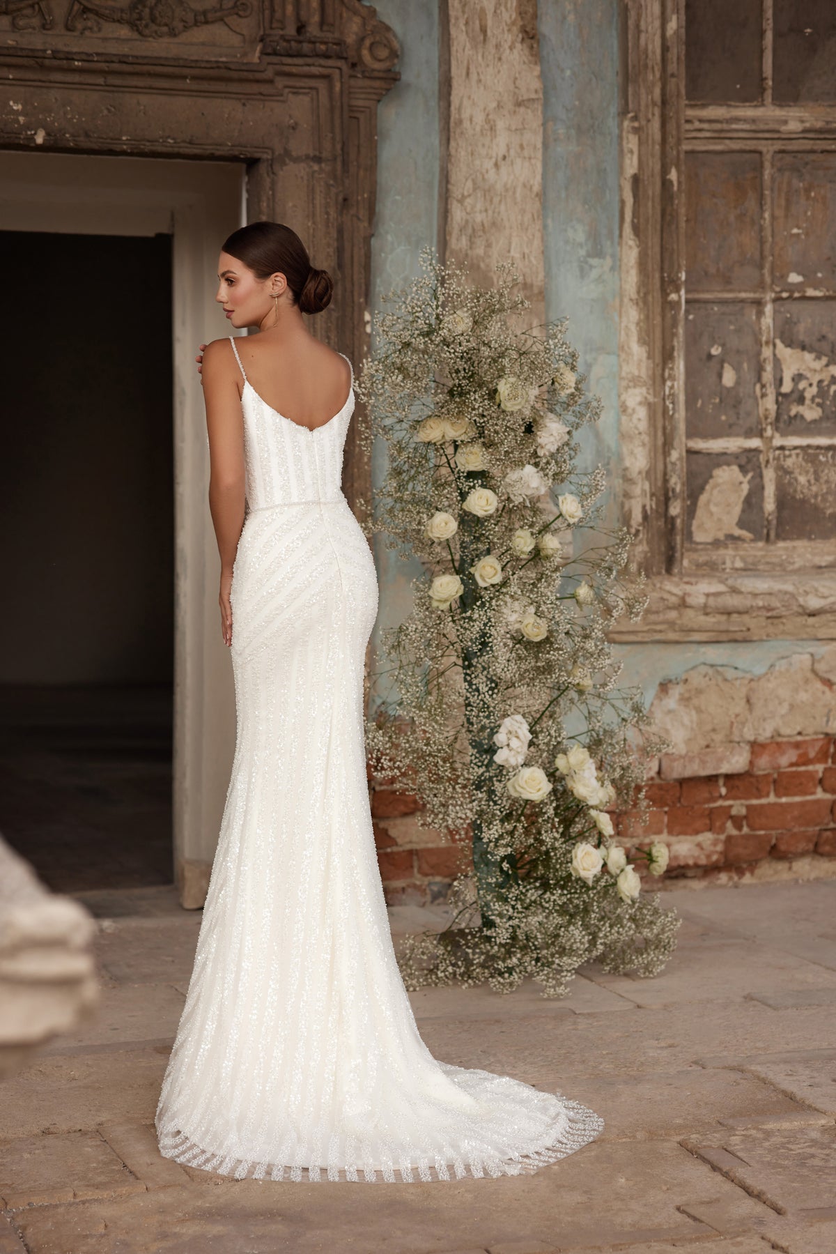 Ivory wedding dress with a low scoop back, thin straps, fitted sheath silhouette, and pooling train