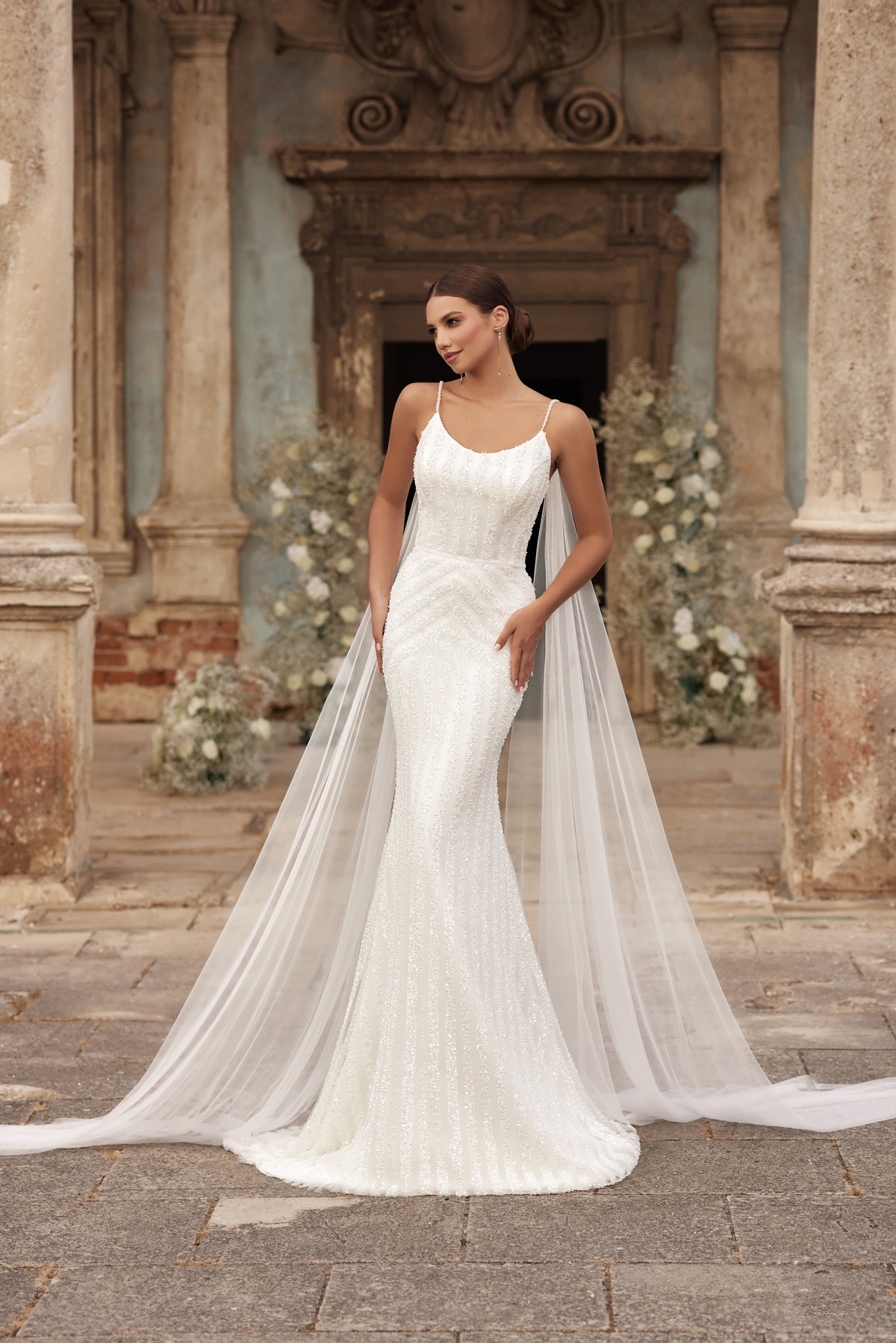 Ivory sheath wedding dress with a beaded scoop neckline, thin straps, and a long sheer train
