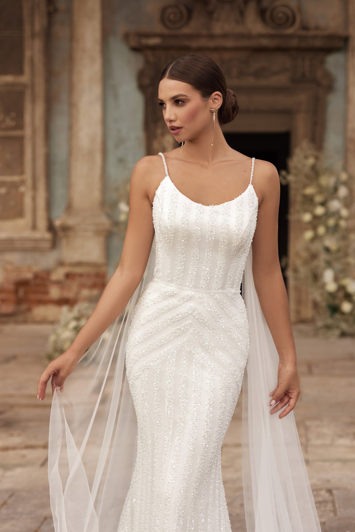 Close-up of an ivory wedding dress with beaded vertical texture, scoop neckline, and slender straps