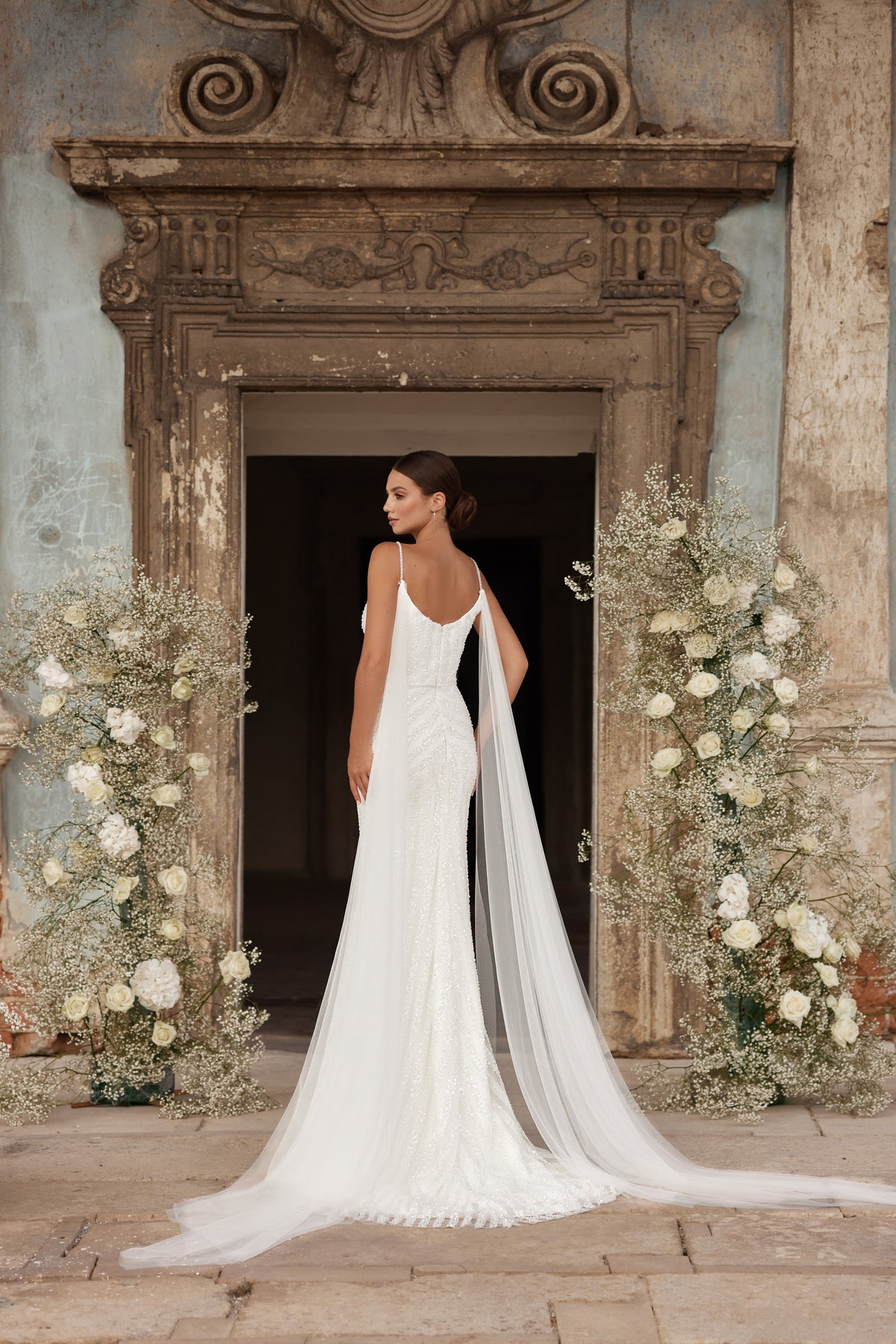Low scoop-back ivory wedding dress with thin straps and a long sheer Watteau train