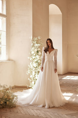 Ivory A-line wedding dress with beaded V-neckline, long sheer sleeves, and a flowing train