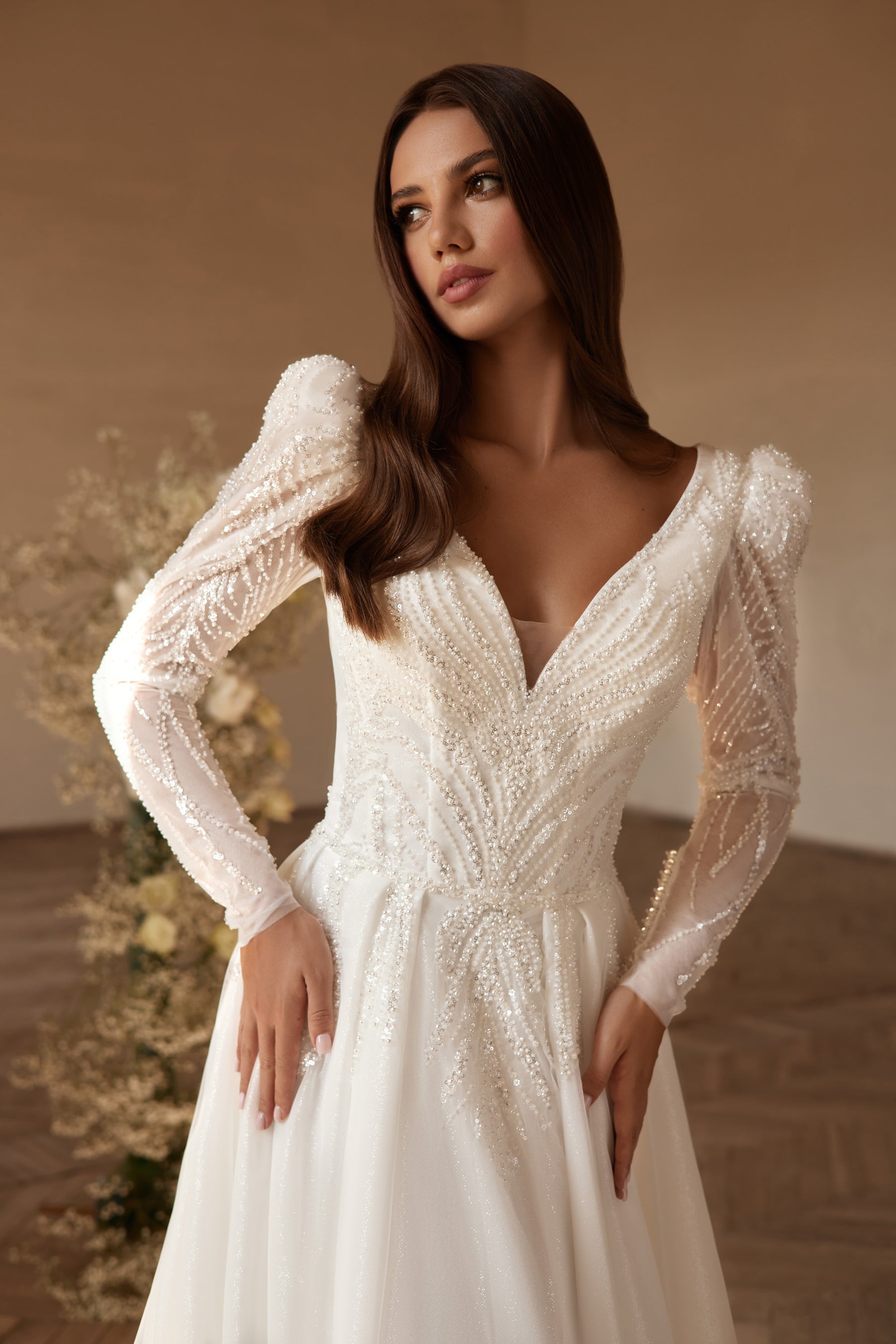 Close-up of an ivory wedding dress with beaded V-neckline, sheer puff sleeves, and embellished bodice