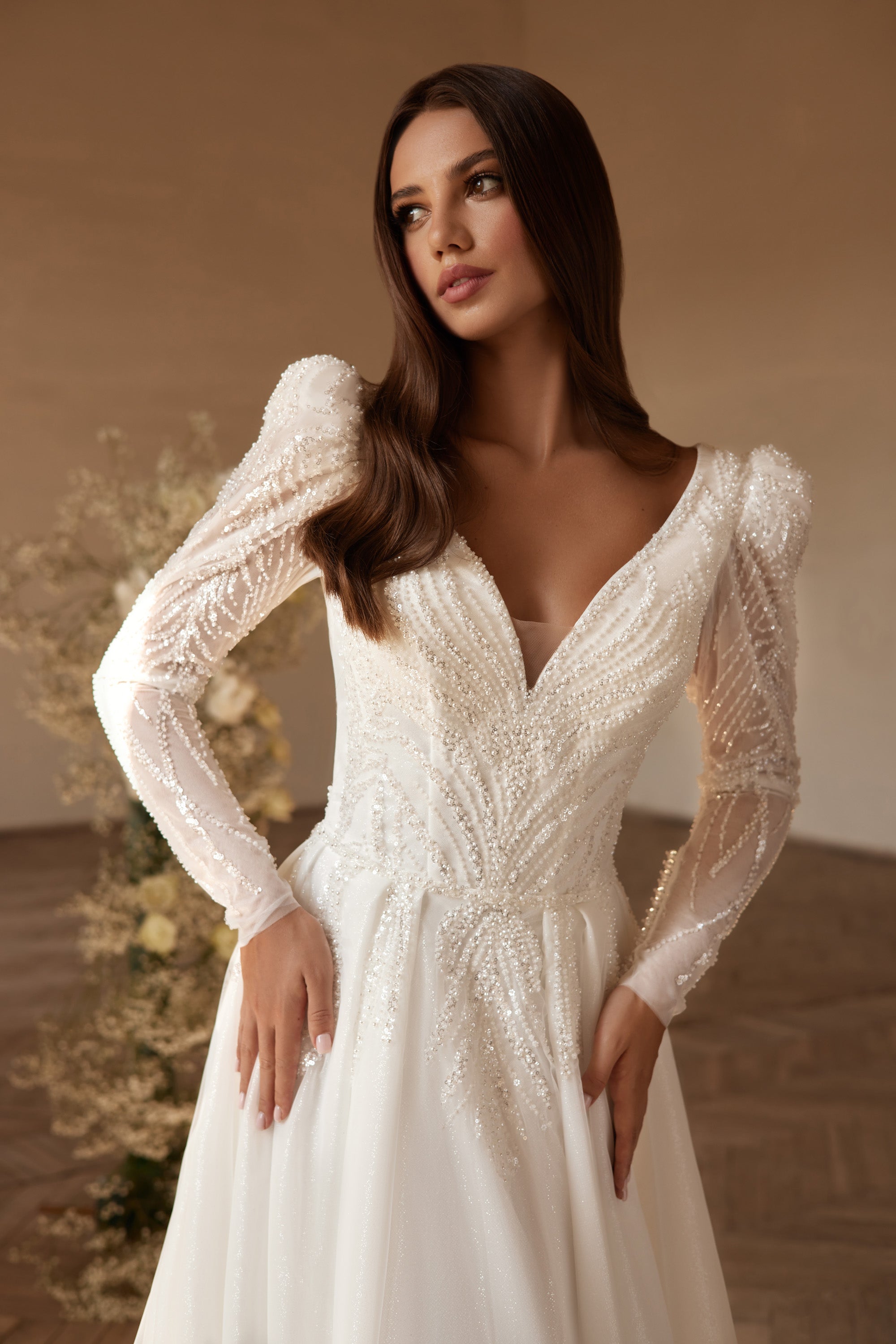 Close-up of an ivory wedding dress with beaded V-neckline, sheer puff sleeves, and embellished bodice