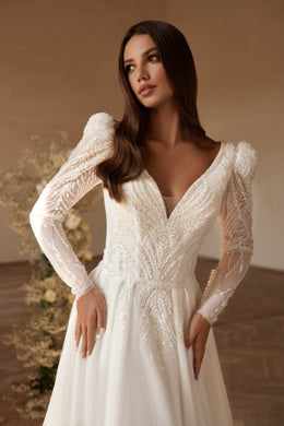 Close-up of an ivory wedding dress with beaded V-neckline, sheer puff sleeves, and embellished bodice