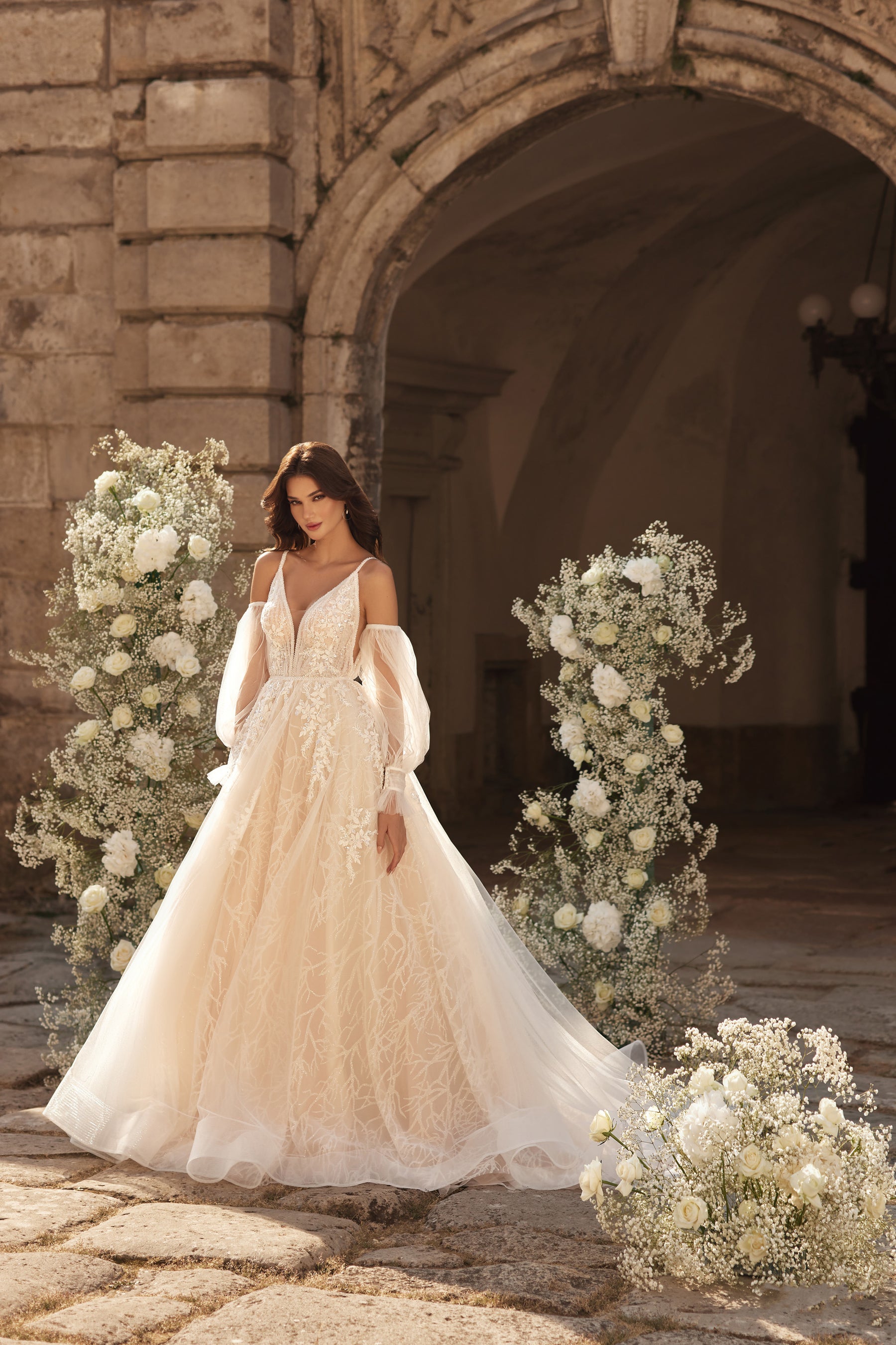 Ivory A-line wedding dress with a deep V-neckline, floral lace, and sheer off-the-shoulder sleeves