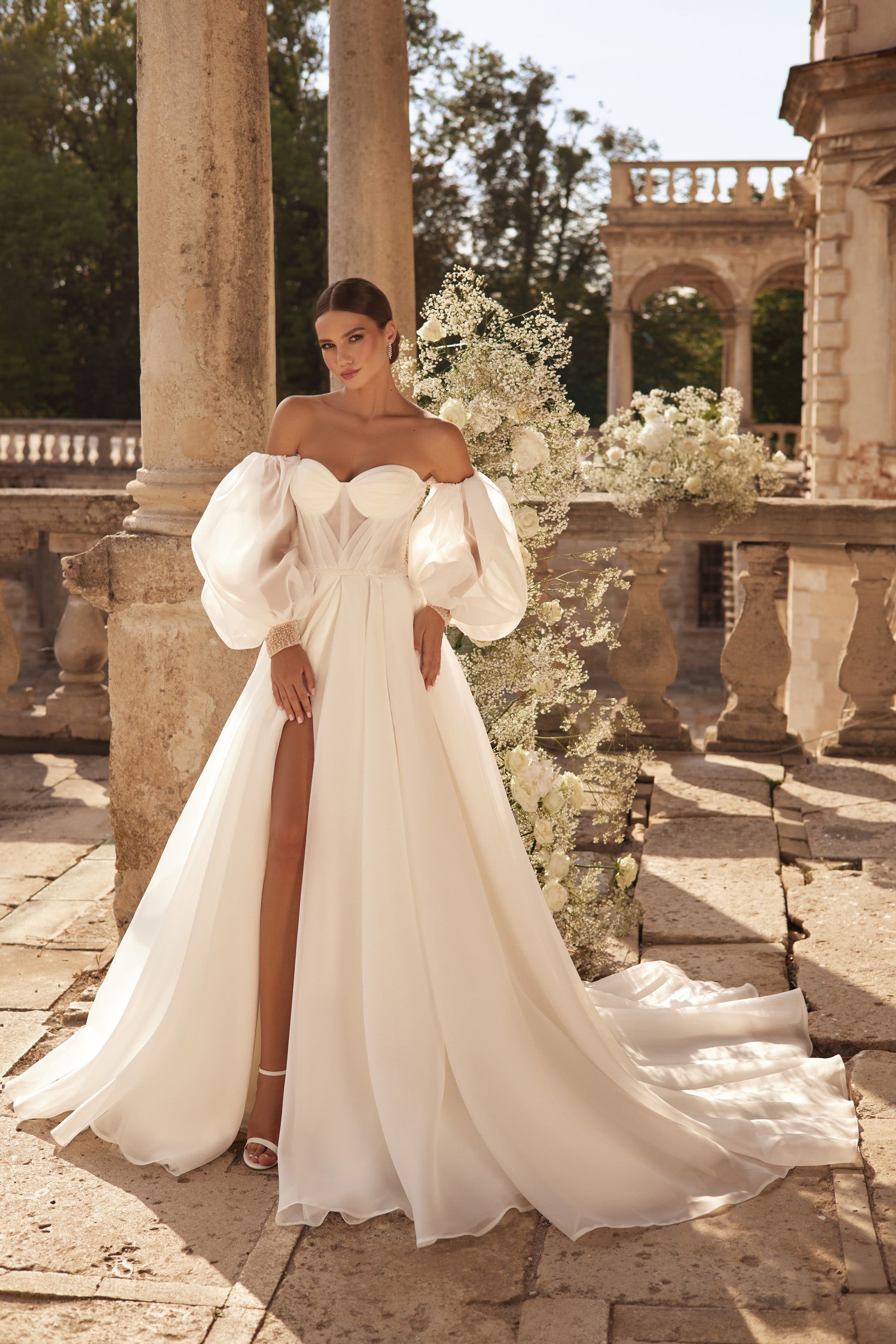 Ivory A-line wedding dress with a sweetheart neckline, puff sleeves, thigh-high slit, and flowing train