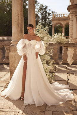 Ivory A-line wedding dress with a sweetheart neckline, puff sleeves, thigh-high slit, and flowing train