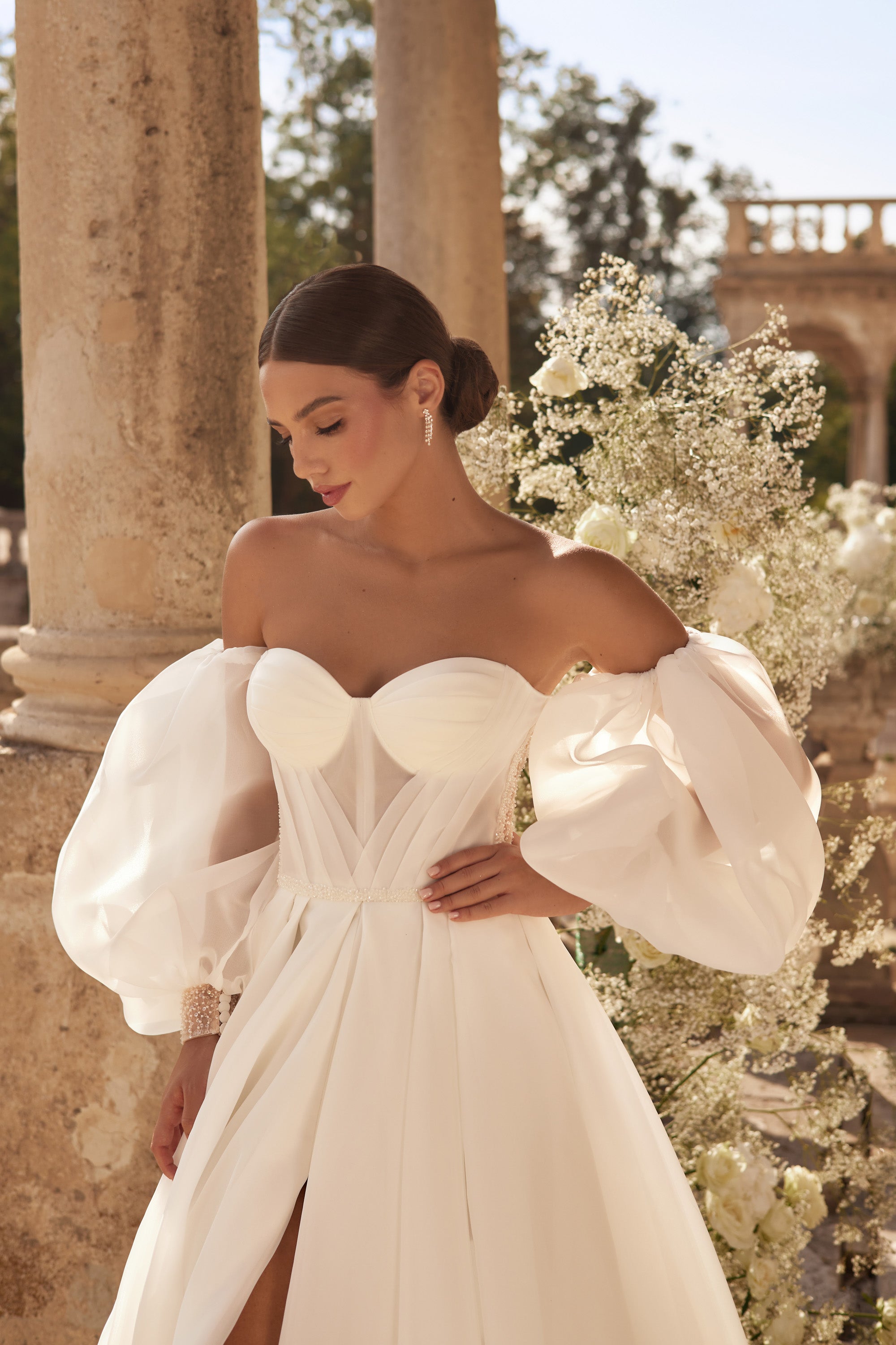 Close-up of an ivory wedding dress bodice with sweetheart neckline, sheer puff sleeves, and pleated detailing