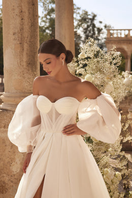 Close-up of an ivory wedding dress bodice with sweetheart neckline, sheer puff sleeves, and pleated detailing