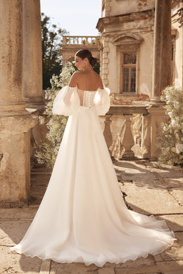 Ivory wedding dress with off-the-shoulder puff sleeves, an open corset-style back, and sweeping train