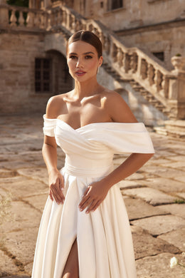 Ivory A-line wedding dress with an off-the-shoulder draped neckline, ruched bodice, and front slit