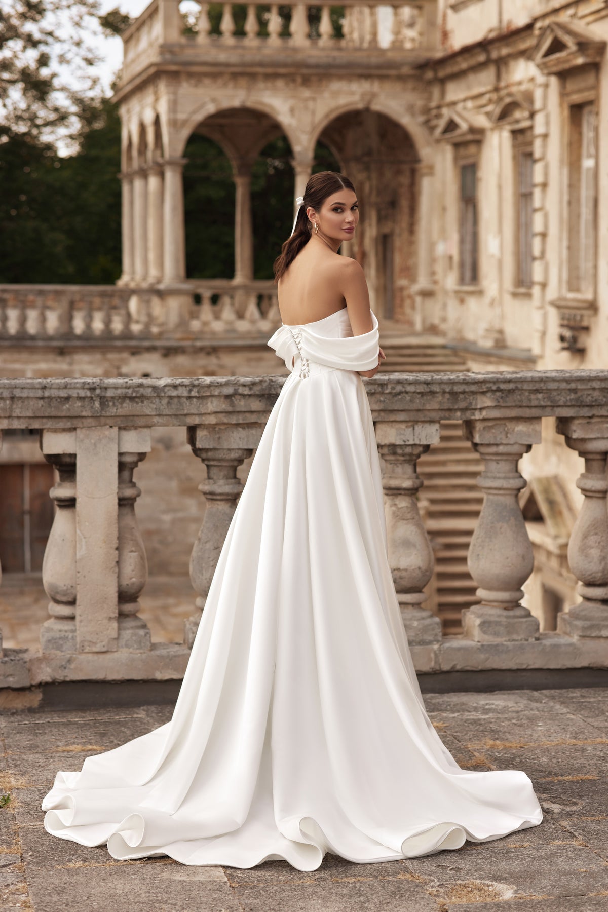 Back view of an ivory wedding dress with an off-the-shoulder neckline, bare upper back, and sweeping train