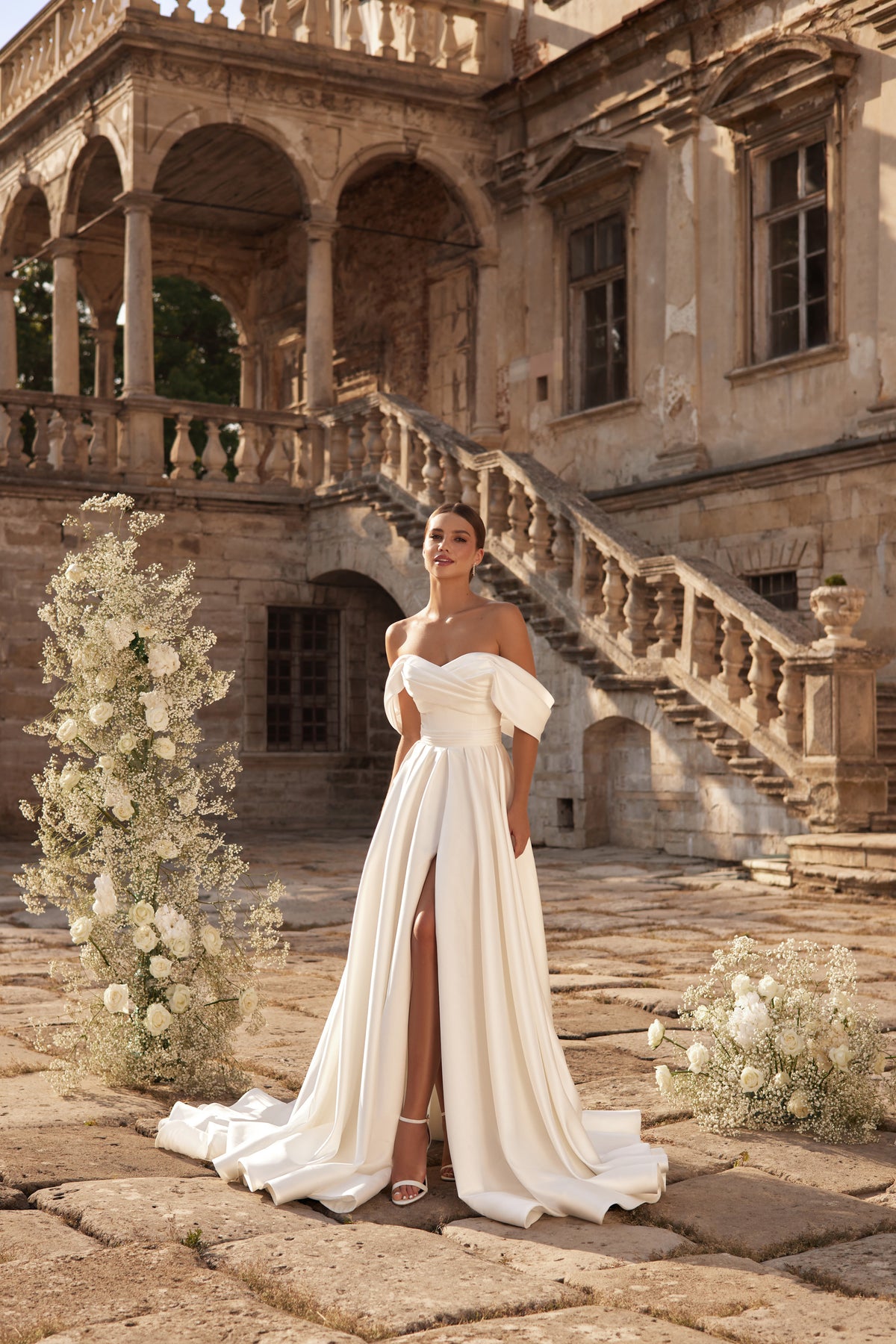Ivory wedding dress with an off-the-shoulder neckline, flowing A-line skirt, front slit, and long train