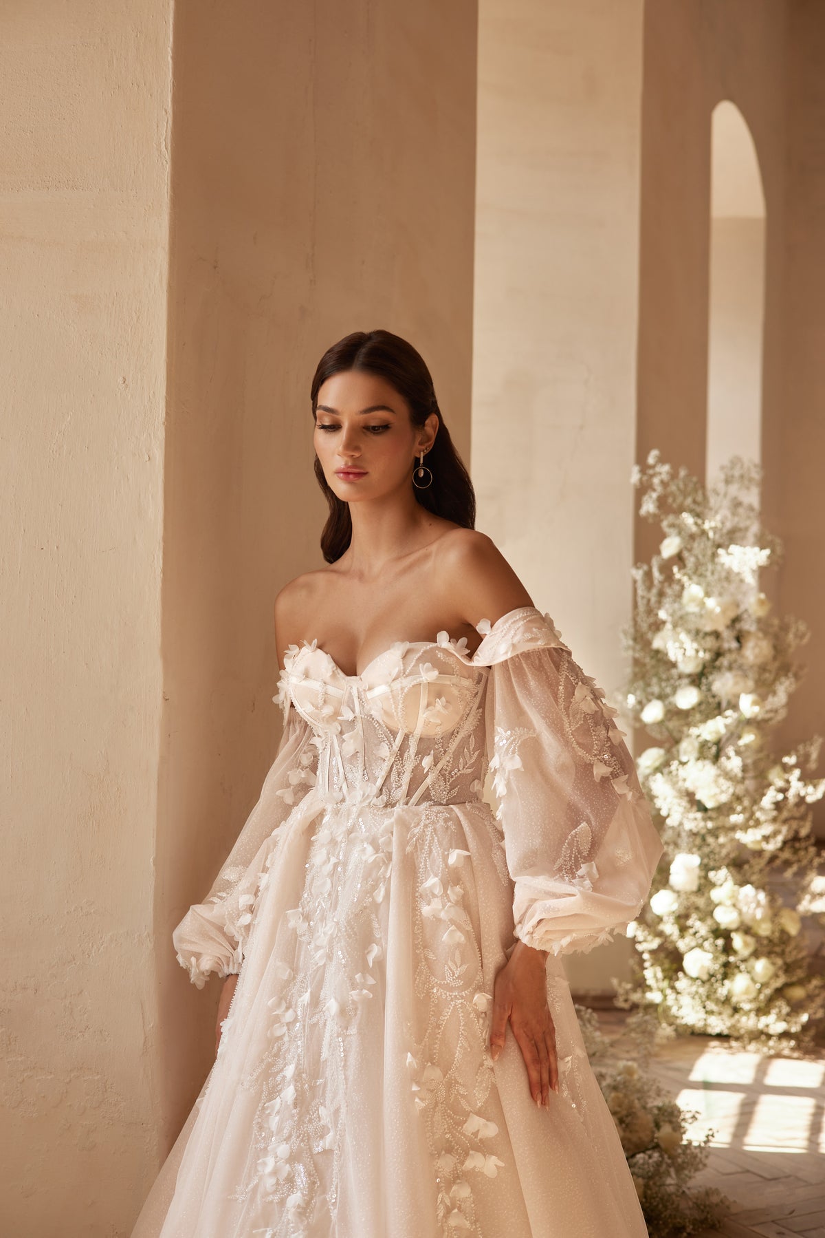 Ivory wedding dress featuring a corset-style bodice, floral appliqués, and voluminous sheer sleeves