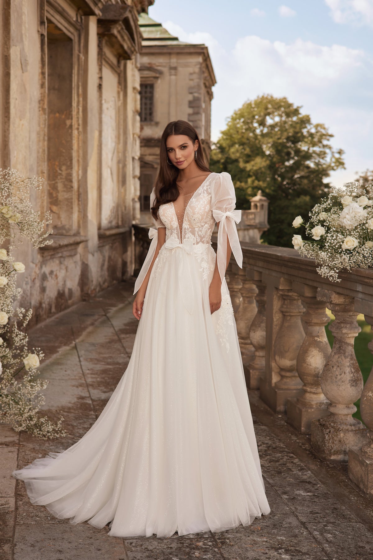 Ivory A-line wedding dress with a deep V-neckline, puff sleeves, and a sweeping train