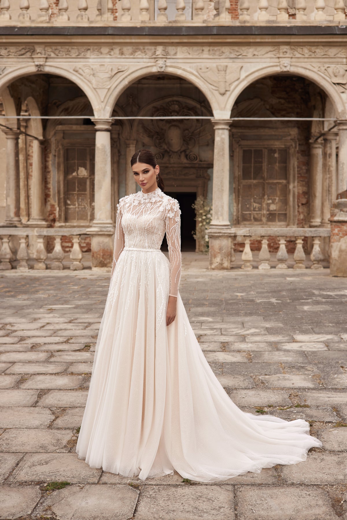Ivory A-line wedding dress with a high illusion neckline, long lace sleeves, embellished bodice, and long train