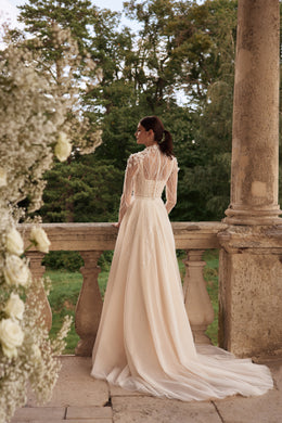 Back view of an ivory wedding dress with a high lace back, long sleeves, flowing A-line skirt, and sweeping train