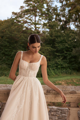 Ivory wedding dress with a square neckline, slender straps, sparkling beaded bodice, and gathered A-line skirt