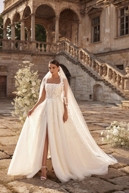 Ivory wedding dress with a beaded floral lace bodice, long sheer sleeves, and a flowing train