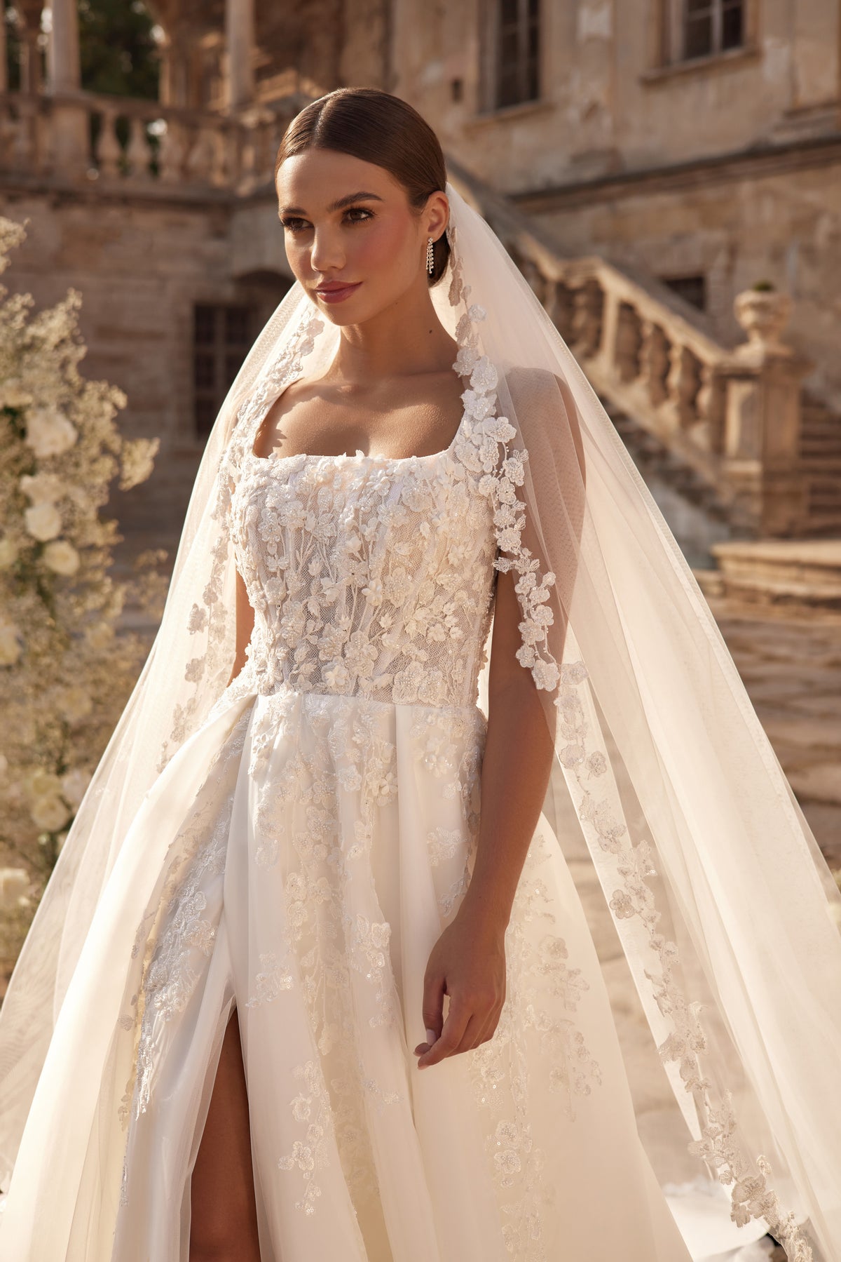 Square-neck wedding dress with intricate floral lace appliqués and sheer long sleeves
